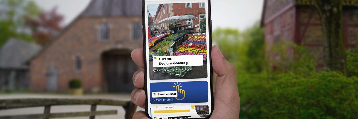 Ein Benutzer präsentiert die neue Webseite der Stadt Vreden auf einem Smartphone im Stadtpark.